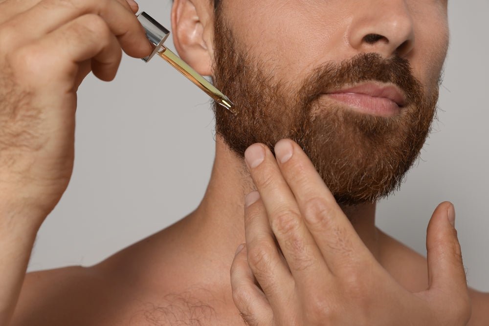 bearded man applies face for him by hairmetto from a dropper to his beard for softness and hydration